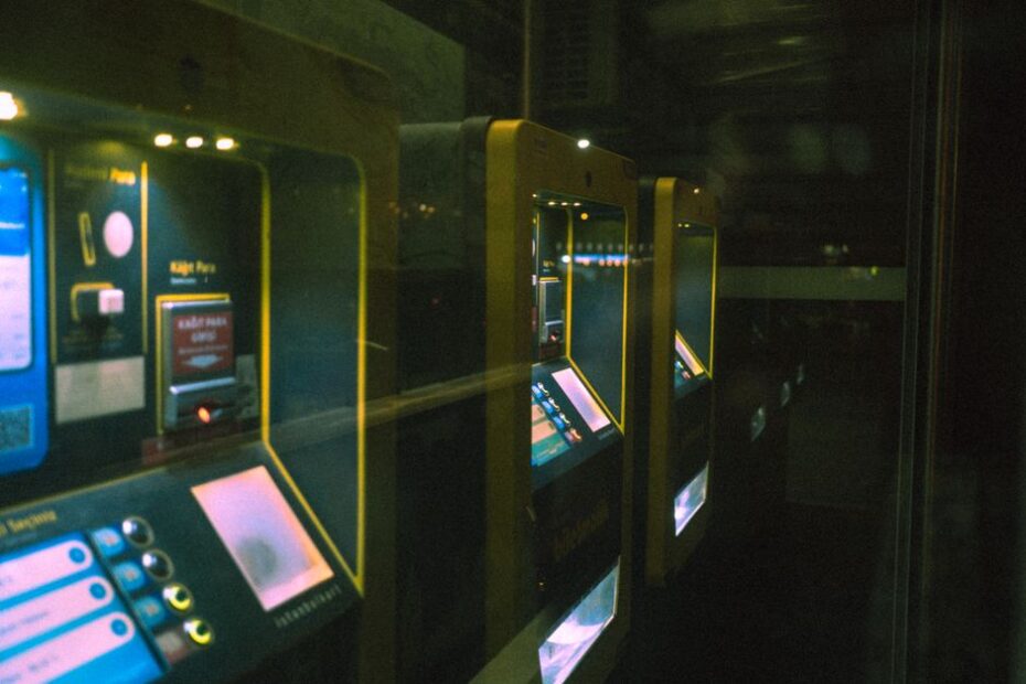 Row of illuminated ticket machines in a dark setting with a reflective perspective.