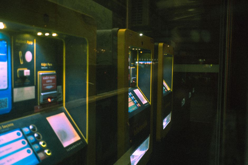 Row of illuminated ticket machines in a dark setting with a reflective perspective.