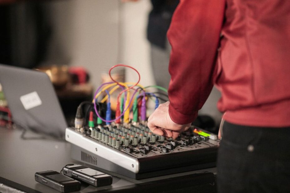 Man adjusting sound mixer in studio for live audio production. Captures focused sound engineering.